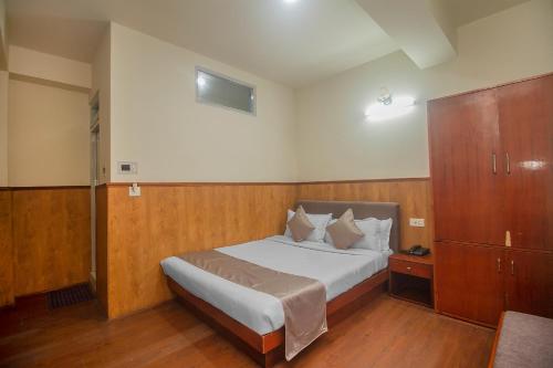 a small bedroom with a bed and a cabinet at Hotel Sakura in Gangtok