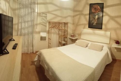 a bedroom with a white bed and a flat screen tv at El descanso de las hadas in San Leonardo de Yagüe
