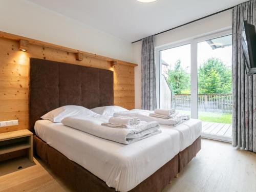 une chambre avec un grand lit avec une grande fenêtre dans l'établissement Apart33 Top 2-4, à Haus im Ennstal