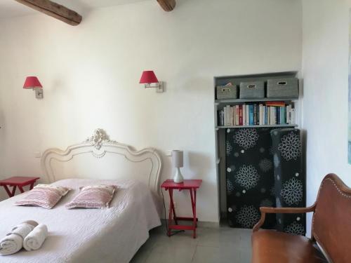 een slaapkamer met een wit bed en een boekenplank bij la bastide aux buis avec piscine in Blauvac