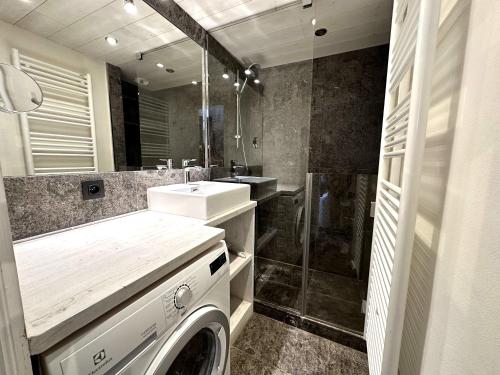 une salle de bain avec une machine à laver et un lavabo dans l'établissement Les Fermes Mégevannes, à Megève