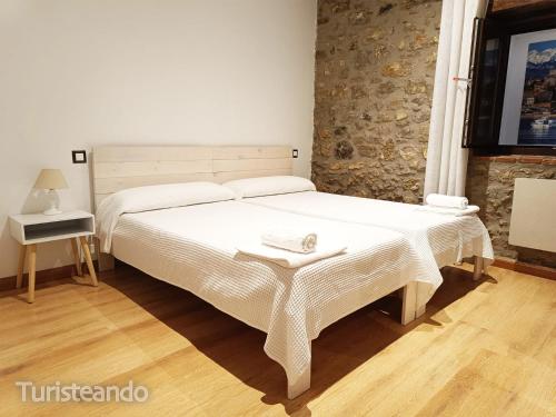 ein Schlafzimmer mit einem großen weißen Bett und einem Tisch in der Unterkunft Apartamento Llerandi 1C - Ideal para dos personas in San Vicente de la Barquera