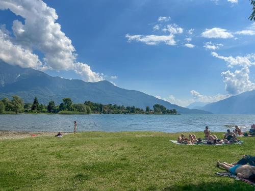 a group of people sitting on the grass near a lake at Dascio Silence Ferienwohnung mit Panorama Balkon in Dascio