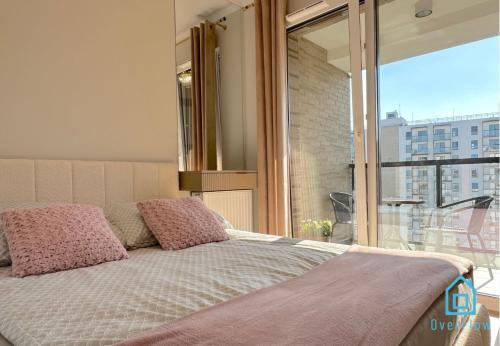 グダニスクにあるLaura Apartment with Sauna & Gym, 5 Min to Baltic Sea & Polsat Plus Arenaの窓付きの部屋(ピンクの枕が備わるベッド1台付)