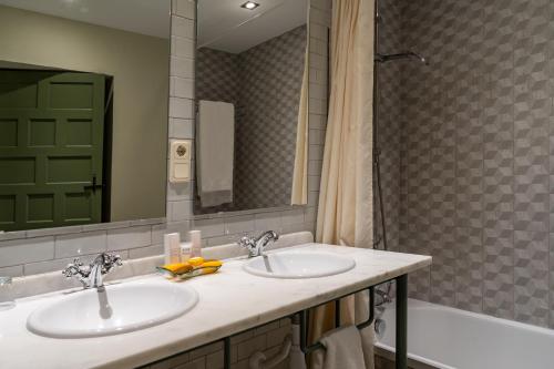 a bathroom with two sinks and a mirror and a tub at Hotel Boutique Molino del Arco in Ronda