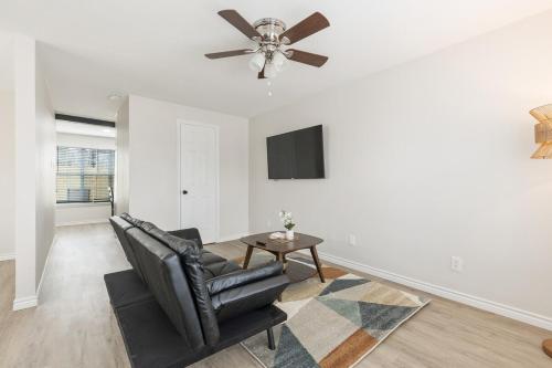 een woonkamer met een zwarte leren stoel en een plafondventilator bij Calmont Guest House in Fort Worth