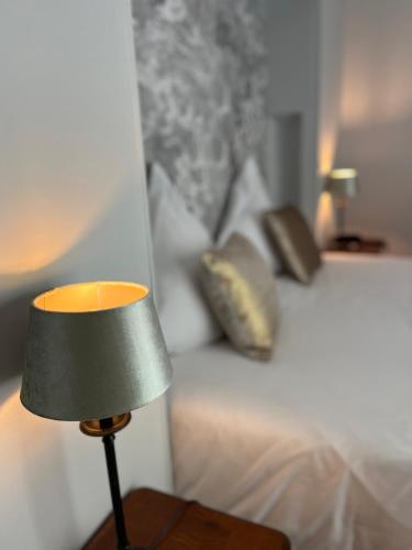 a lamp on a table next to a bed at Hotel de la Gaichel in Eischen