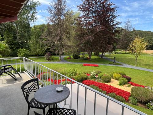 a balcony with a table and chairs and a garden at Hotel de la Gaichel in Eischen