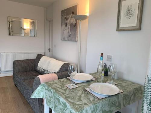 a living room with a table with glasses and a couch at Modern, Stylish lodge with Paddock Views in Sandwich