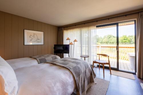 a bedroom with two beds and a television and a balcony at Laceby Manor - Spa & Golf Resort in Laceby