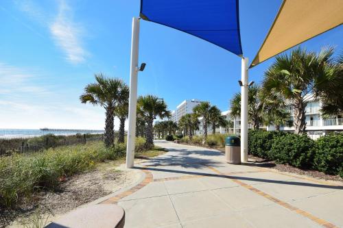 a sidewalk next to the beach with a blue umbrella at Holiday Sands North "On the Boardwalk" in Myrtle Beach