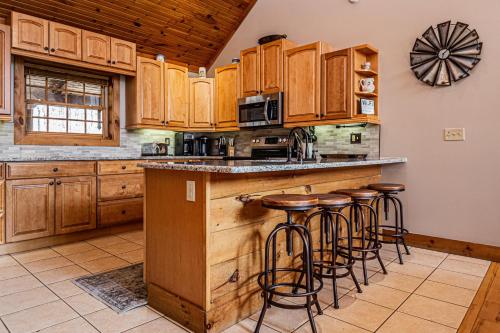 a kitchen with wooden cabinets and bar stools at Rock Lodge Cabin in McHenry