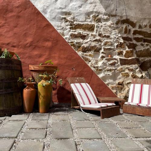 two chairs sitting on a patio next to a wall at Obidos Rural Chic House in Usseira