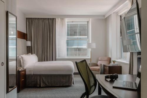 a hotel room with a bed and a desk at Club Quarters Hotel Faneuil Hall, Boston in Boston