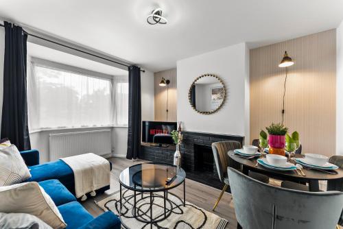 a living room with a blue couch and a table at Stylish 4-Bed Cambridge Stay - Garden & Games Room in Cherry Hinton