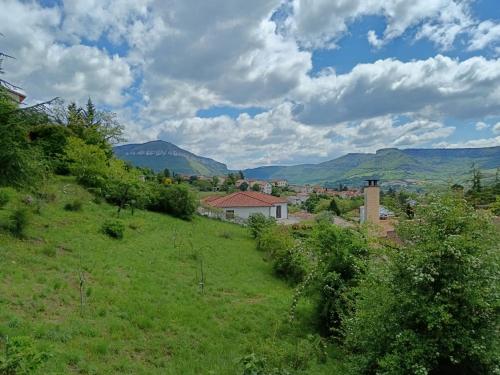 a green field with a house and mountains in the background at Gîte des Grands Causses in Millau