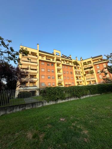 a large yellow and orange building with a grass field at Cozy suite with terrace in Castellanza