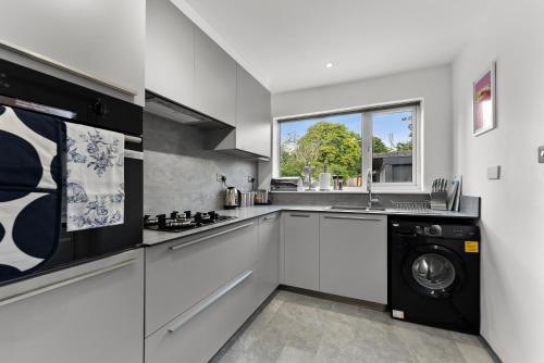 a kitchen with a washer and dryer in it at Stylish 4-Bed Cambridge Stay - Garden & Games Room in Cherry Hinton