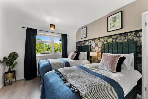 a bedroom with two beds and a window at Stylish 4-Bed Cambridge Stay - Garden & Games Room in Cherry Hinton