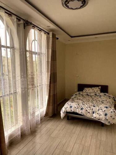 ein Schlafzimmer mit Bett und großen Fenstern in der Unterkunft Comfortable house in Solai in Nakuru