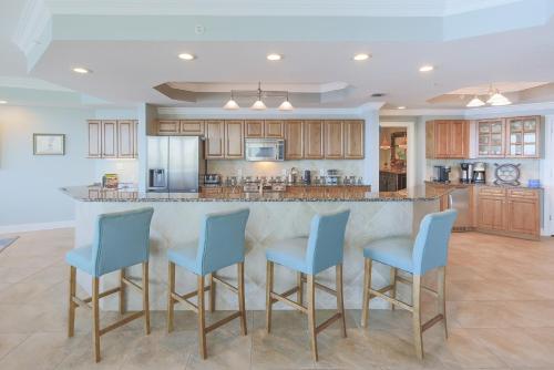 eine Küche mit einer Bar mit vier blauen Stühlen in der Unterkunft Phoenix on the Bay 1333 - Poseidon House condo in Orange Beach