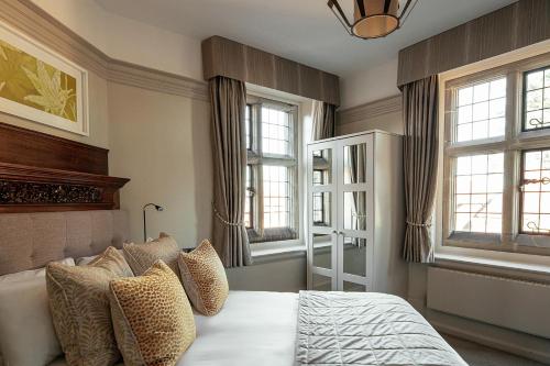 a bedroom with a bed with pillows and windows at Fanhams Hall, Exclusive Collection in Ware