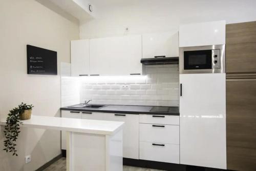 une cuisine avec des armoires blanches et un micro-ondes dans l'établissement 2 pièces centre-ville tout équipé, à Nîmes