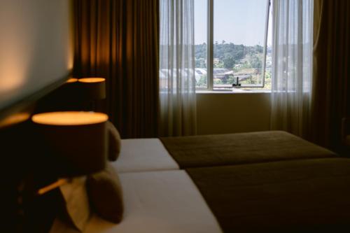 a hotel room with a bed and a large window at Hotel Conde de Agueda in Águeda