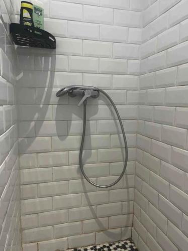 La salle de bains est pourvue d'une douche avec un tuyau et de carrelage blanc. dans l'établissement 2 pièces centre-ville tout équipé, à Nîmes