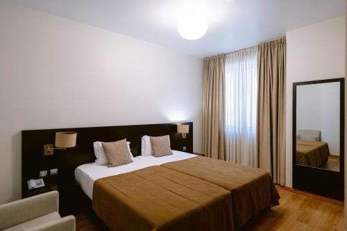 a hotel room with a large bed and a mirror at Hotel Conde de Agueda in Águeda