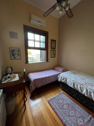 two beds in a room with a window and a table at TSEliot Bed&Breakfast in Banfield