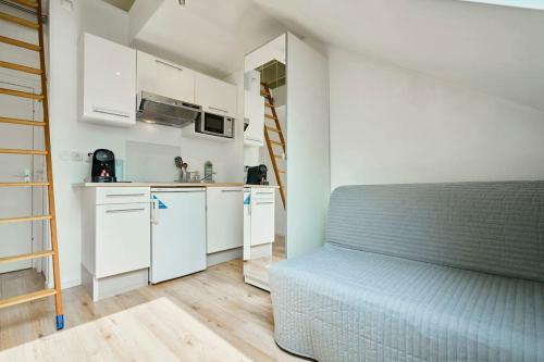 - une cuisine avec des placards blancs et un canapé bleu dans une chambre dans l'établissement La nouveauté Lilloise, à Lille