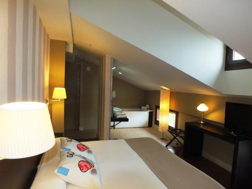 a hotel room with a bed with a lamp and a bathroom at Hotel Puerta del Arco in Tudela de Duero