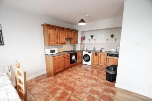 Una cocina con gabinetes de madera y piso de baldosas. en Cosy, Cute and Modern Apartment steps to the beach, en Bundoran