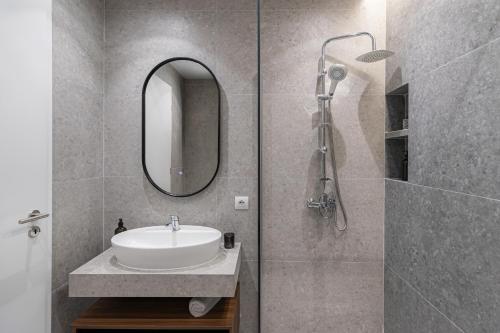a bathroom with a sink and a shower with a mirror at Prado Apartments in Pristina