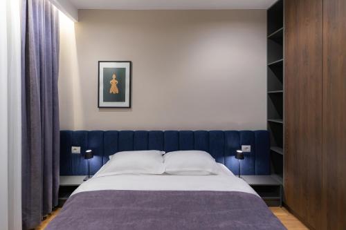 a bedroom with a bed with a blue headboard at Prado Apartments in Pristina