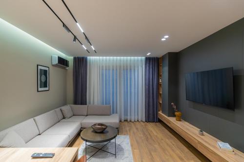 a living room with a white couch and a tv at Prado Apartments in Pristina