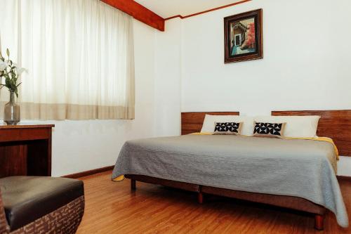a bedroom with a bed and a window and a chair at Hotel Rex in Toluca