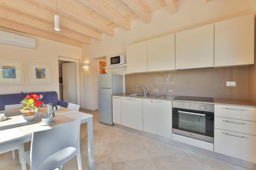 a kitchen with white cabinets and a dining table at Camping Village Le Calanchiole in Capoliveri