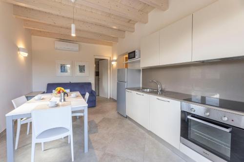 a kitchen with white cabinets and a table and a table and chairs at Camping Village Le Calanchiole in Capoliveri