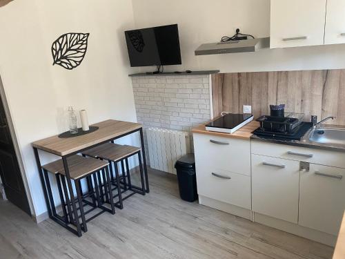 - une cuisine avec un évier et une table avec des tabourets dans l'établissement Gîte carpe Diem, à Ligré