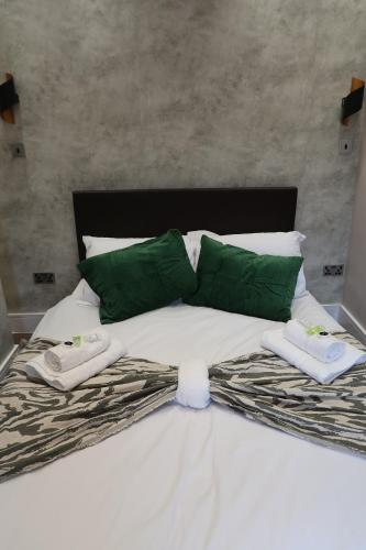 a bed with green pillows and towels on it at Casa Bella In Sherborne's Historic Quarterlocal in Sherborne
