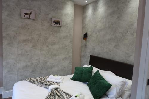 a bedroom with a bed with white sheets and green pillows at Casa Bella In Sherborne's Historic Quarterlocal in Sherborne