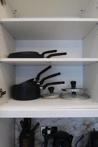 a shelf with pots and pans on a stove at Casa Bella In Sherborne's Historic Quarterlocal in Sherborne