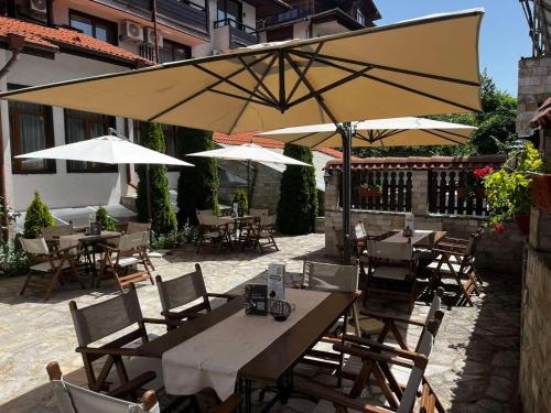 an outdoor patio with tables and chairs with umbrellas at Hotel Iceberg Bansko in Bansko