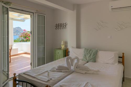 a bedroom with a white bed with a view of the ocean at ALTHEA HOUSES in Alinda