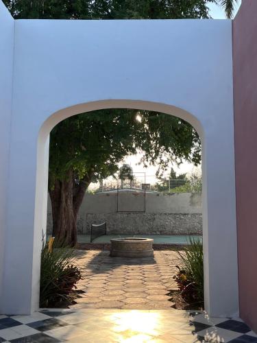 an archway with a tree and a bench under it at ConSentido Tamarindo in Mérida