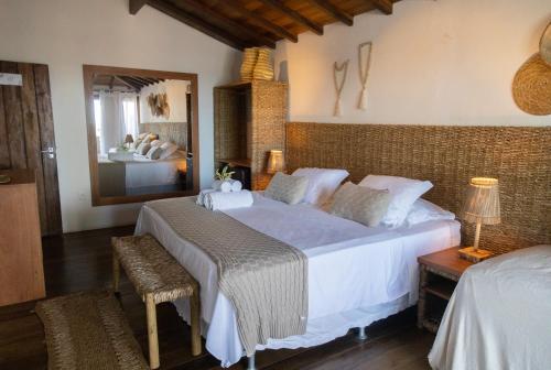 a bedroom with a large white bed and a mirror at Pousada Vila do Mar in Caraíva
