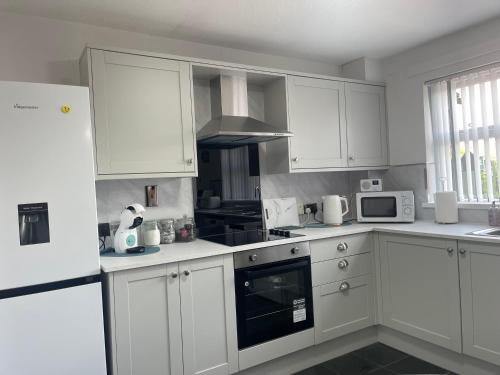 a white kitchen with white cabinets and appliances at Belfast Grand Central Living 5 Minutes Walk From Grand Central Station in Belfast