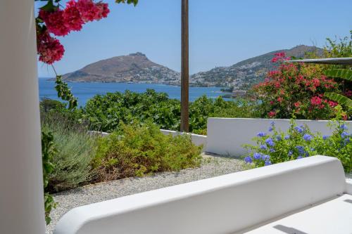 a white bench in a garden with a view of the ocean at ALTHEA HOUSES in Alinda